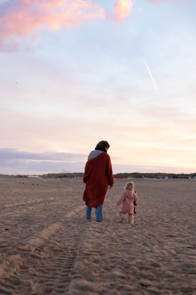 moeder en kind lopen in winterkleding op strand fotoshoot Utrecht nieuwegein buiten