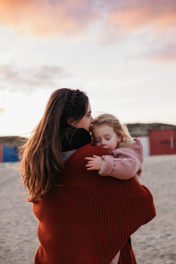 moeder en kind knuffelen in winterkleding op strand fotoshoot Utrecht nieuwegein buiten